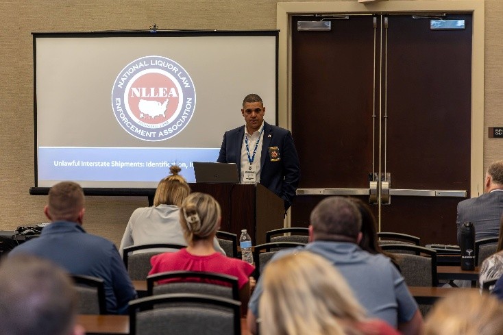Christopher Template standing beside a projection screen talking to a group of seated people